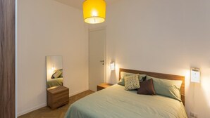 Ein Schlafzimmer mit Bett, Nachttischen, einem Spiegel und einer Wandleuchte.