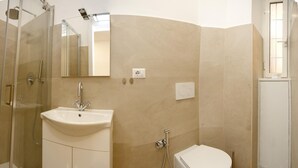 Ein modernes Badezimmer mit Duschkabine aus Glas, einem weißen Waschbecken und einer Toilette.