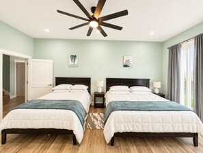 Ein Schlafzimmer mit zwei Betten, einem Deckenventilator und einem Fenster mit Vorhängen.