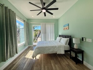 A bedroom with a bed, a nightstand, a ceiling fan, and a view of a balcony. - Ocean Crest Luxury Villa - 6BR w/Pool (Camp Bay)