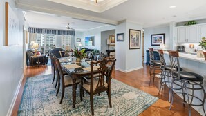 Un vaste espace dédié à la salle à manger, avec une grande table en bois, de nombreuses chaises et un tapis à motifs.
