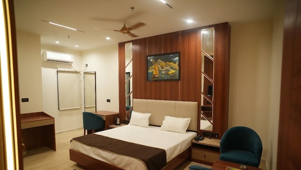 A modern hotel room with a large bed, a desk, a chair, and a wardrobe. - Hotel Devki Inn (Gorakhpur)
