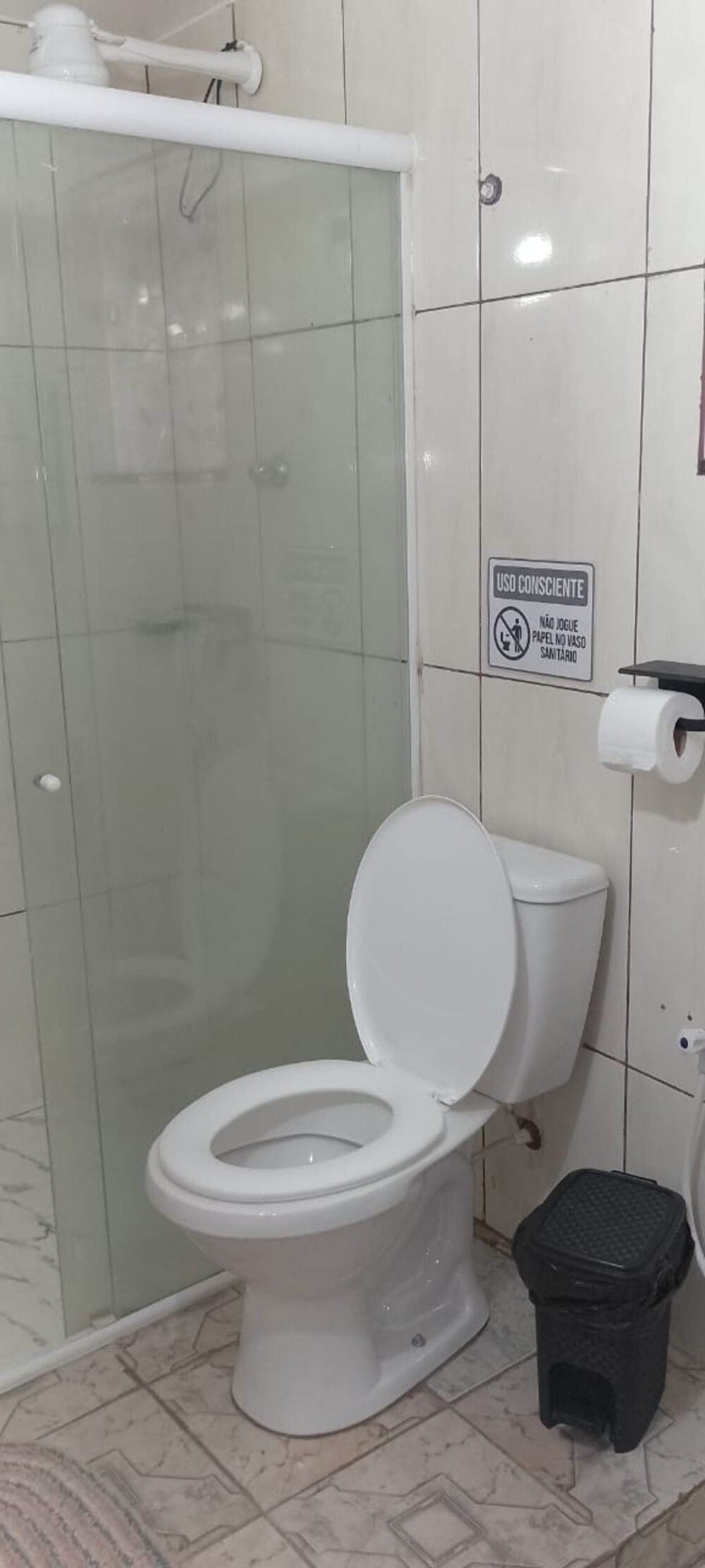 Ein Badezimmer mit Toilette, Dusche und Mülleimer.