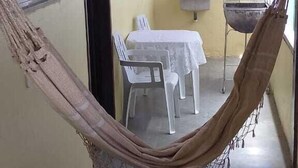 A room with a hammock, a table with chairs, a sink, and a window. - Flats dos Fernandes  (Búzios)
