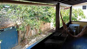A covered outdoor area with a hammock, a small table, and chairs. - Flats dos Fernandes  (Búzios)