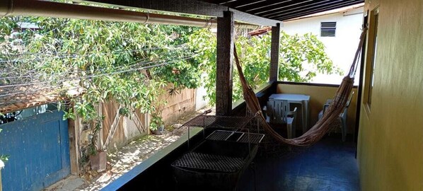 A covered outdoor area with a hammock, a small table, and chairs.