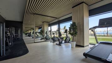 A gym with exercise equipment, large windows, and a view of the outdoors.