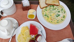 Ein Frühstücksbrett mit Toast, Eiern, Ananas und einem Teekännchen.