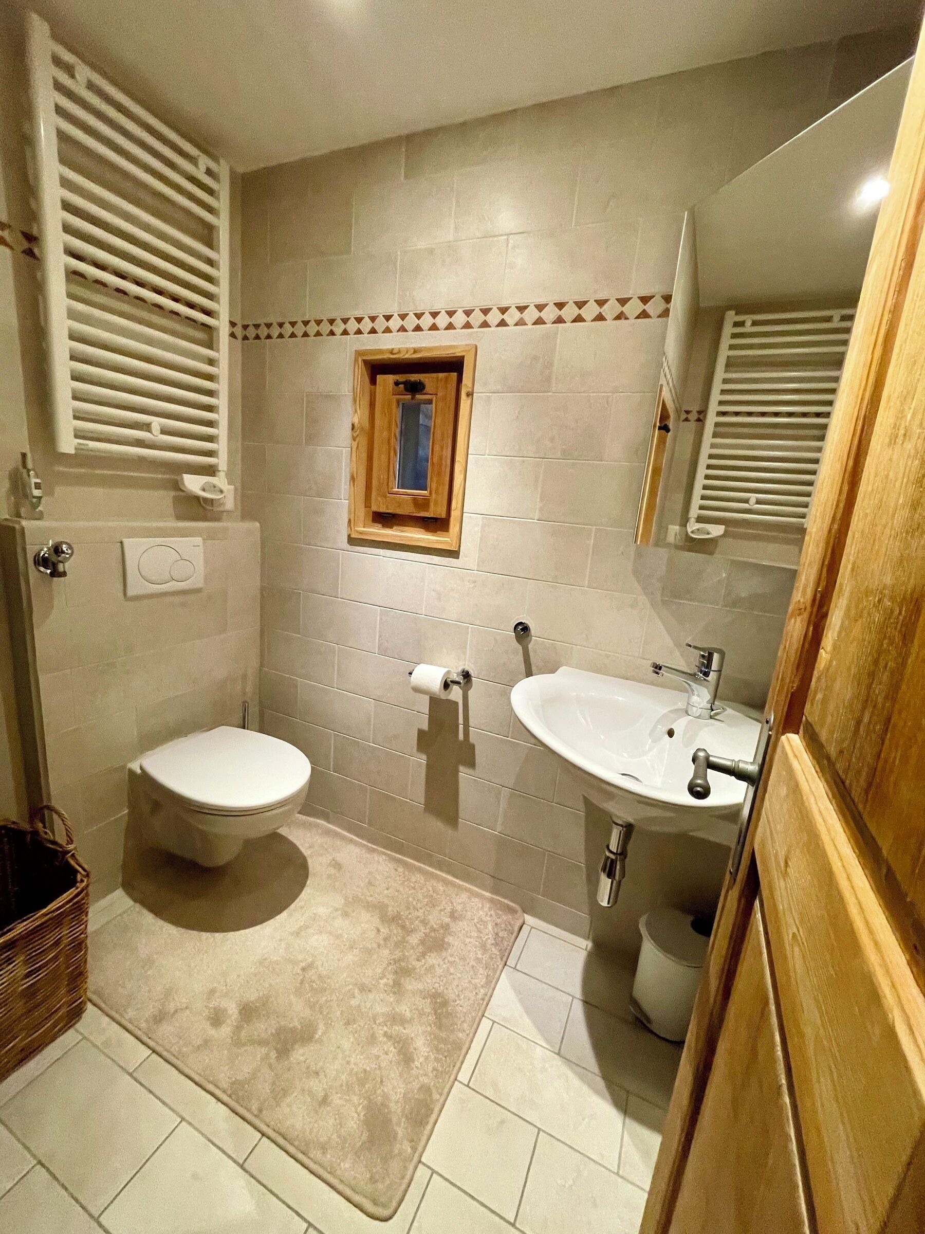 A bathroom with two toilets, a sink, and a small window.