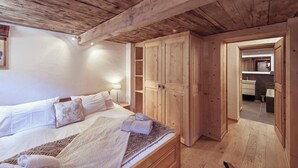 A bedroom with a wooden ceiling, a large bed with pillows, a wardrobe, and a bathroom visible through an open door. - 4-room chalet for 6 people in the heart of the old village of Grimentz: 1 bedroom with double bed an (Grimentz)