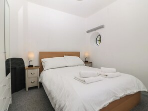 A hotel room with a single bed, two bedside tables, a round window, and a wall-mounted light fixture. - Seaview Hafod Y Graig (Talsarnau)