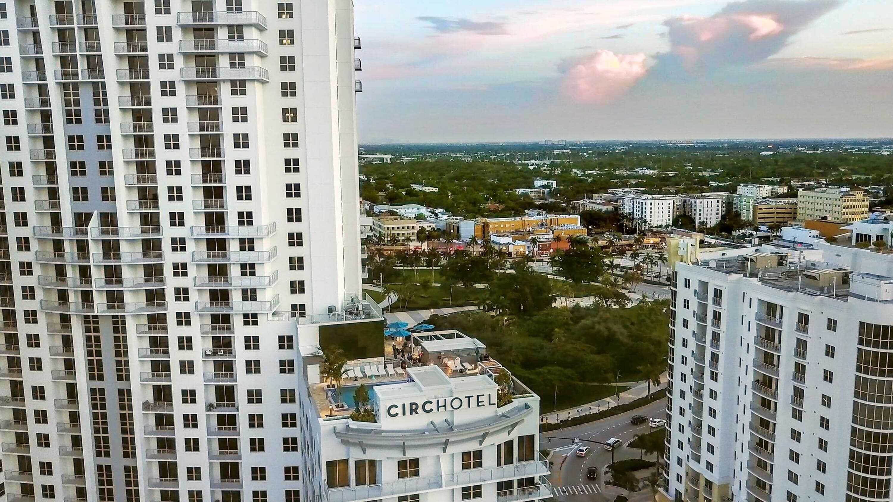 A high-rise hotel with multiple floors, a rooftop pool area, and a view of the surrounding cityscape.