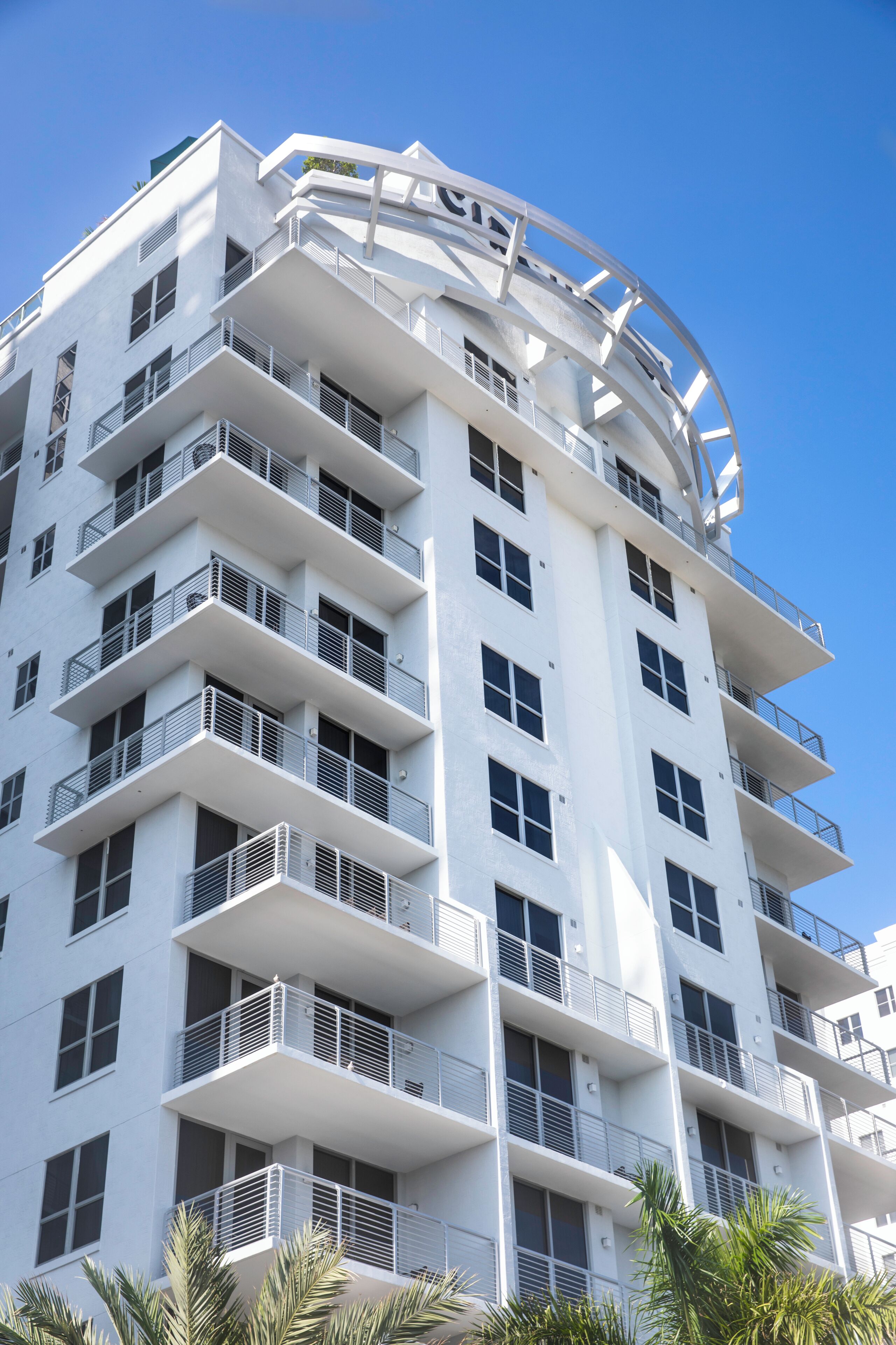 A multi-story building with balconies, large windows, and a circular architectural feature at the top.