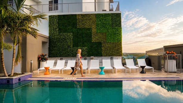 A pool area with a modern design, including a green wall, lounge chairs, and a clear blue pool. - CIRC Hotel By Hosteeva (Hollywood)