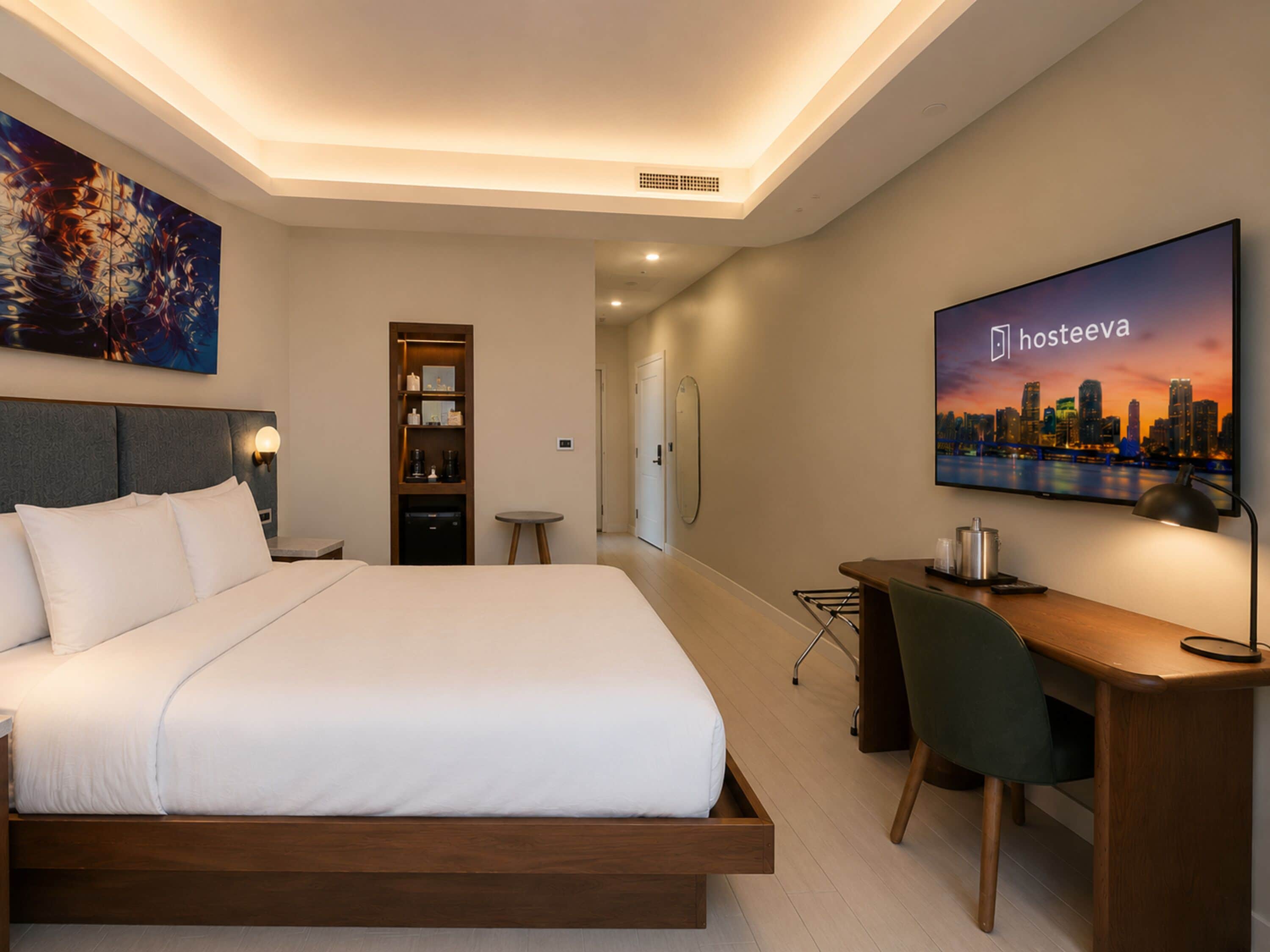 A hotel room with a bed, a desk, a chair, a television, and a bookshelf.