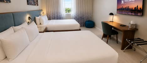 Habitación de hotel con dos camas, un escritorio, una silla, un televisor y una ventana con cortinas.