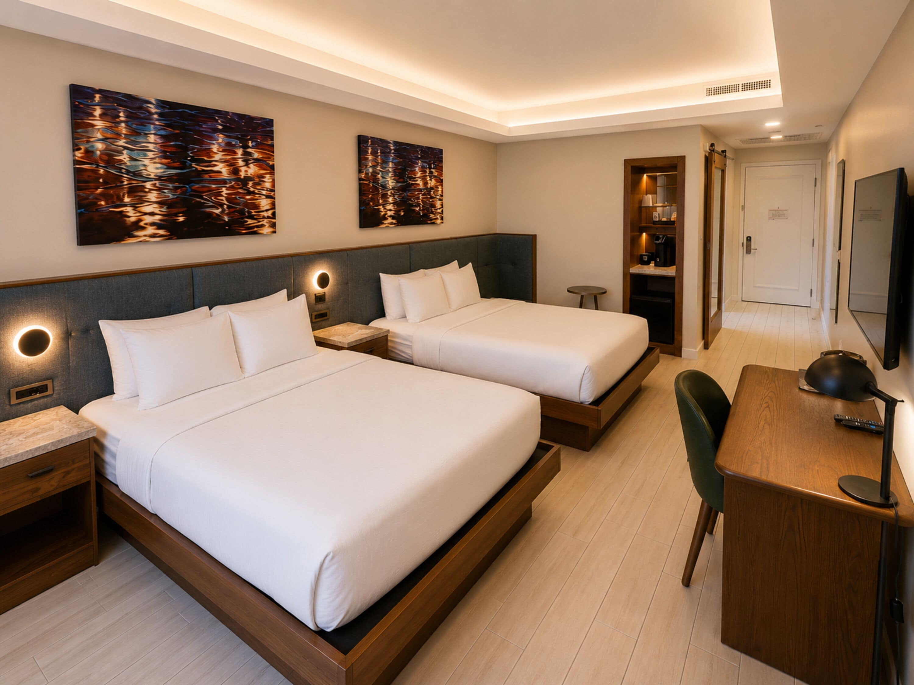 Een hotelkamer met twee bedden, een bureau, een stoel, een televisie en kunst aan de muur.