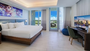 A modern hotel room with a large bed, a desk with a chair, a television, and a balcony with a city view. - CIRC Hotel By Hosteeva (Hollywood)