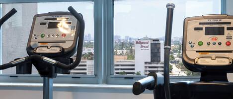 Two exercise machines in a room with a large window.
