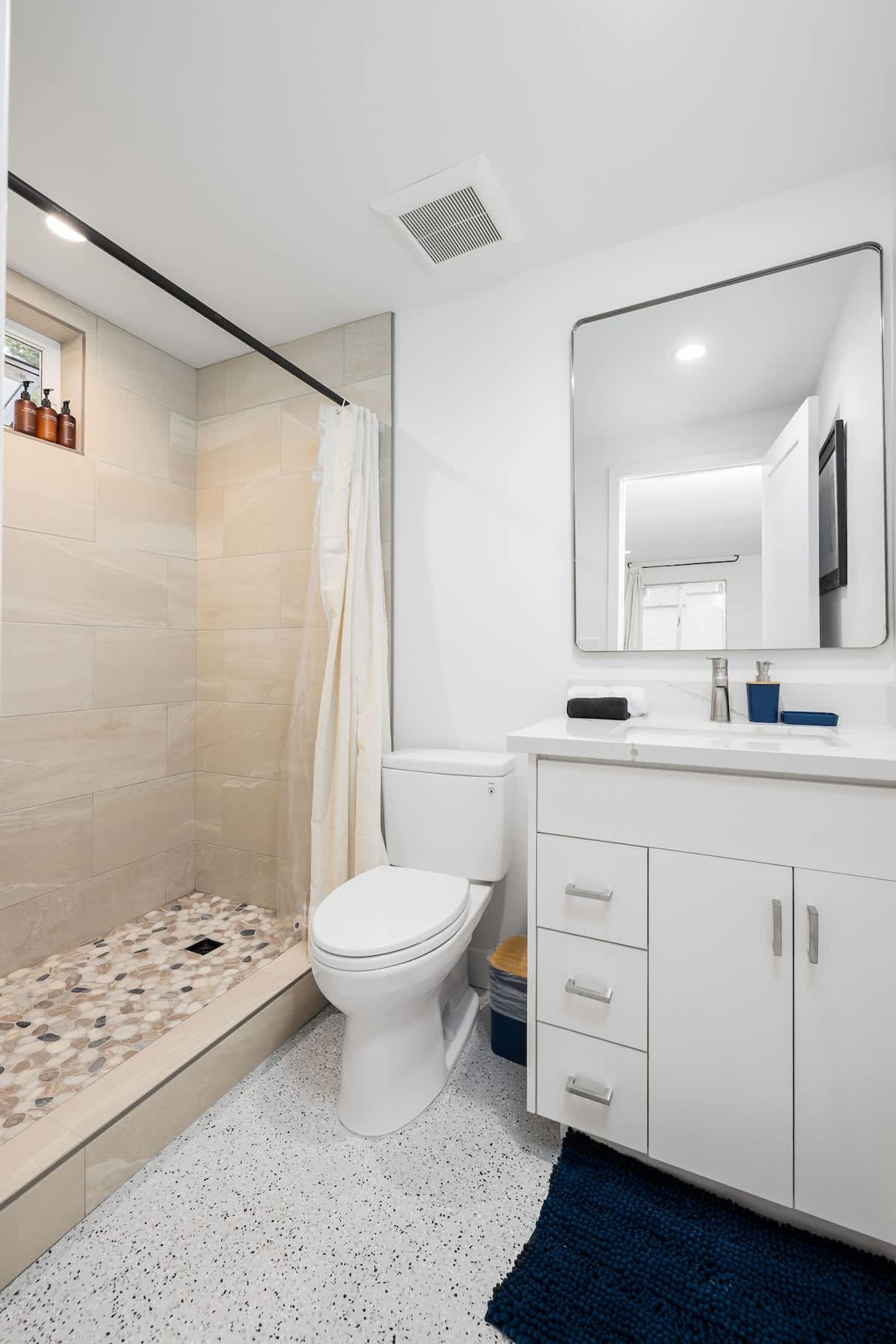 Une salle de bain moderne équipée d’une douche, de toilettes et d’un meuble-lavabo.