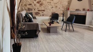 Ein Wohnzimmer mit Steinwand, Kamin, einer Uhr und einem schwarzen Sessel.
