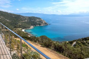 A coastal landscape with a clear view of the sea, a dirt path, and a metal railing. - Luxurious Architect-designed Property Pool sea View (Cargese)
