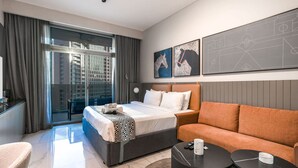 A modern hotel room with a bed, sofa, and a desk with a computer. - Stayshort - Studio in Business bay Sleeps 2 With City Views (Dubai)