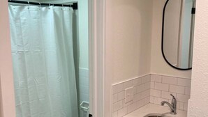 Un baño con inodoro, lavamanos y cortina de ducha.