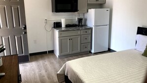 Una camera d'albergo compatta con angolo cottura, un letto e una porta.
