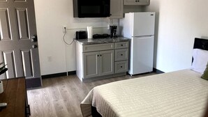 A compact hotel room with a kitchenette, a bed, and a door. - Boutique Motel in Akron (Akron)