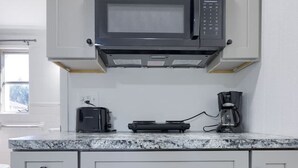 Cozinha com armários brancos, micro-ondas embutido, torradeira e cafeteira.