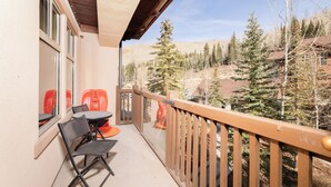 A balcony with a wooden railing, a table, and two chairs. - Powder Stash (with AC unit!) by Cottonwood Lodging (Solitude)