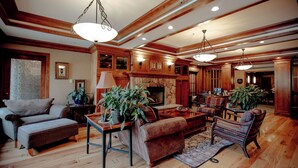 A spacious living room with wooden floors, a fireplace, and a large chandelier. - Powder Stash (with AC unit!) by Cottonwood Lodging (Solitude)