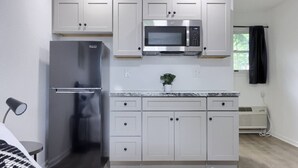 Een kleine keuken met een roestvrijstalen koelkast, een magnetron en witte keukenkastjes.