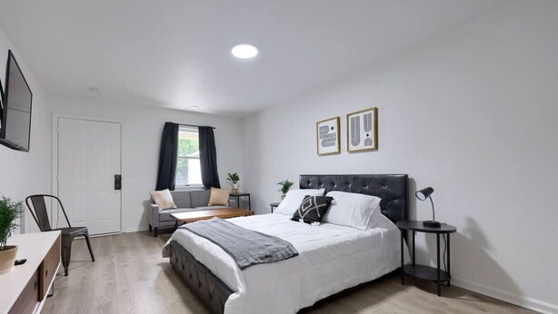 Een moderne slaapkamer met een groot bed, een bureau, een stoel en een raam met gordijnen.