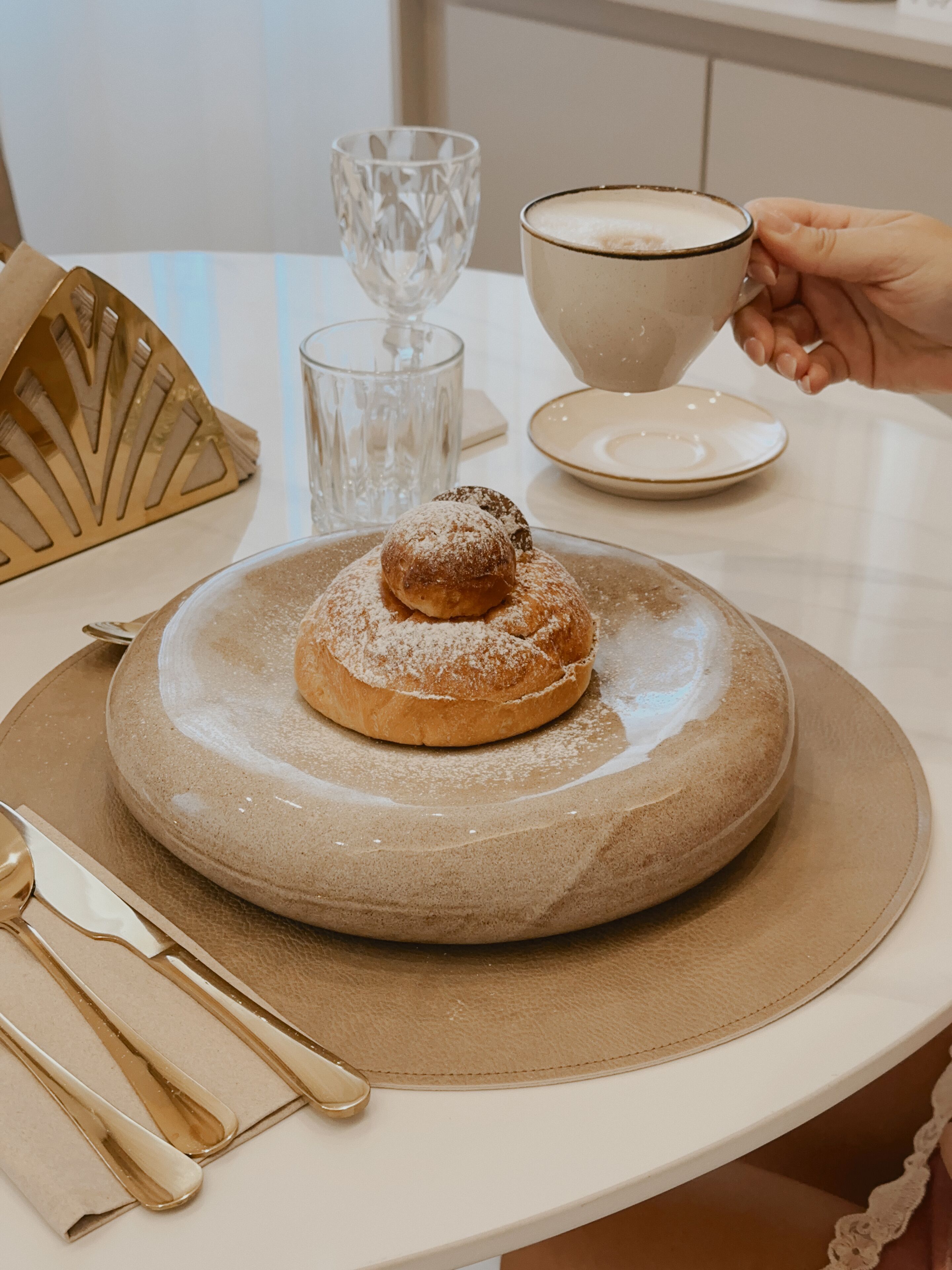 A dessert on a plate with a cup of coffee and a glass on a table.