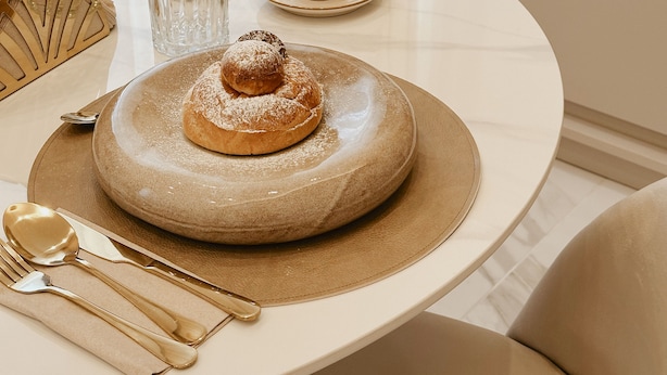 Una mesa con un plato de postre, una taza y cubiertos.