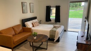 A hotel room with a bed, a sofa, a coffee table, and a desk. - Boutique Motel in Strasburg (Ronks)