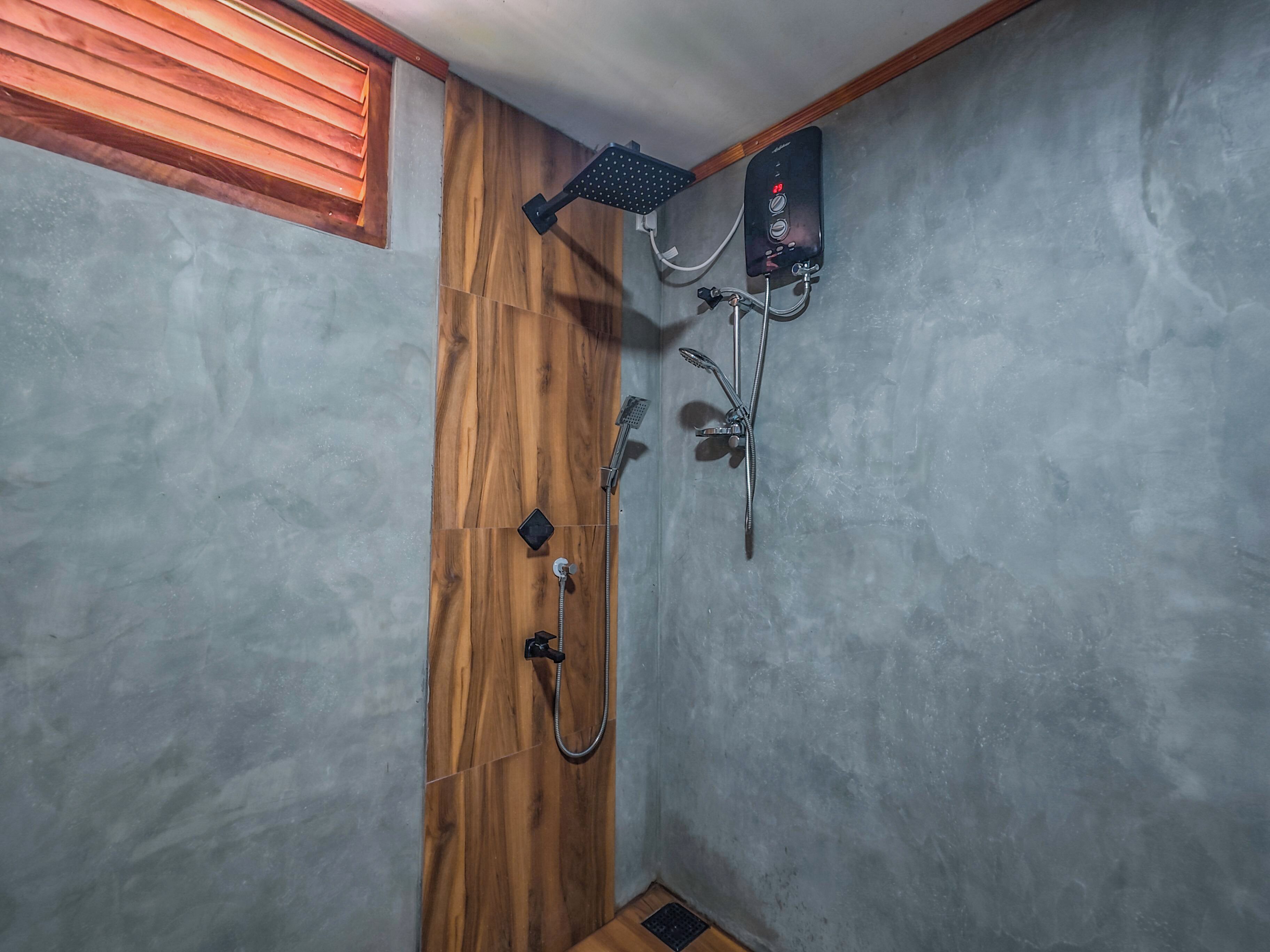 A shower area with a wooden door, a handheld showerhead, a wall-mounted control panel, and a rain shower head.