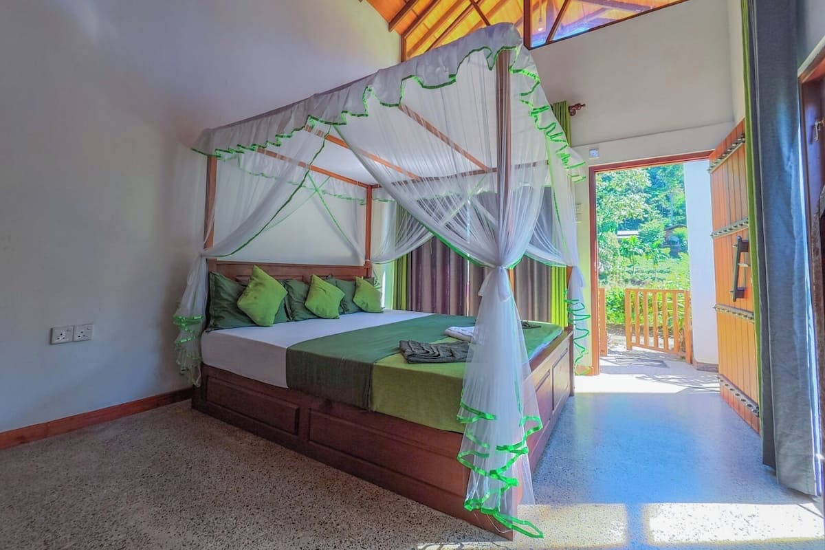 Una cama con dosel, almohadas verdes y cabecera de madera.