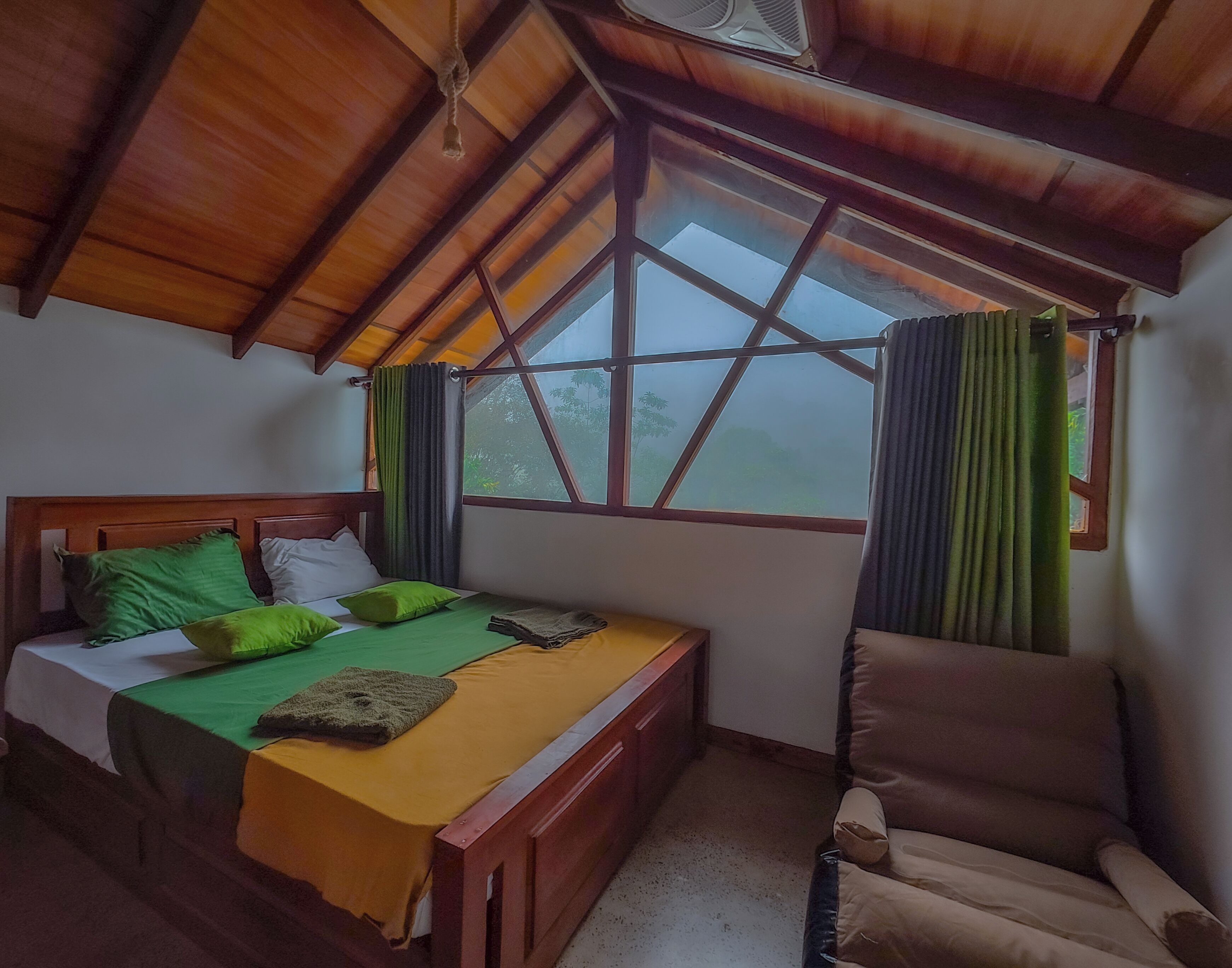Een kamer met een bed, een stoel en een raam met gordijnen.