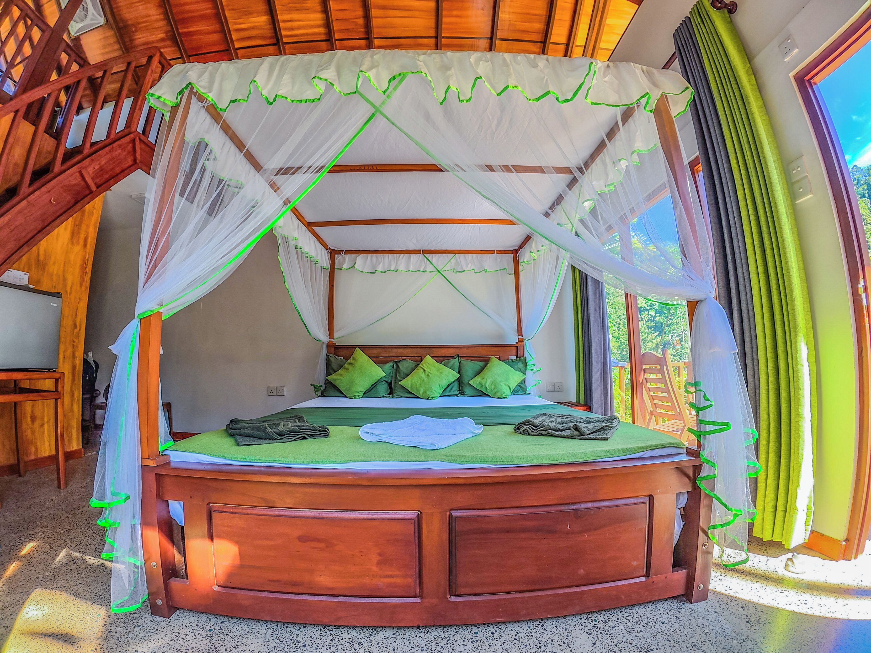A bed with a canopy, green pillows, and a wooden headboard.