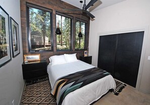 Ein Schlafzimmer mit Bett, Fenster, Deckenventilator und einem schwarzen Kleiderschrank.