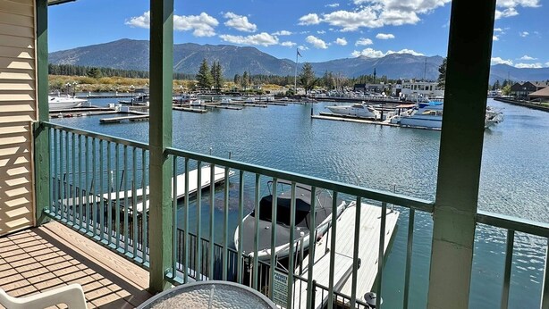 Um terraço coberto com vista para uma marina e montanhas.