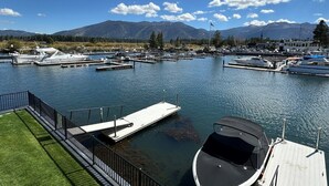 Uma marina com barcos atracados, uma área gramada e montanhas ao fundo.