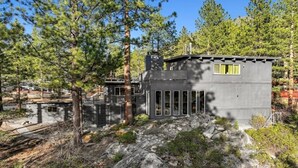 Una cabaña moderna con base de piedra, ventanas amplias y chimenea.