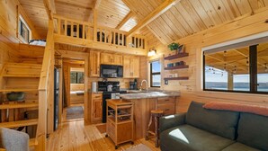 Un interior de cabaña con cocina, comedor y sofá.