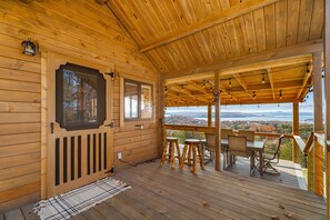 Une cabane en bois dotée d’un porche abrité, d’un coin repas avec une table et des chaises, et offrant une vue sur le paysage environnant.