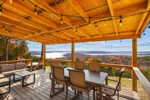 A wooden deck with a table and chairs, overlooking a scenic view of a lake and forest. - P-Bay Gobblers Overlook 1 Bedroom Home (Branson West)