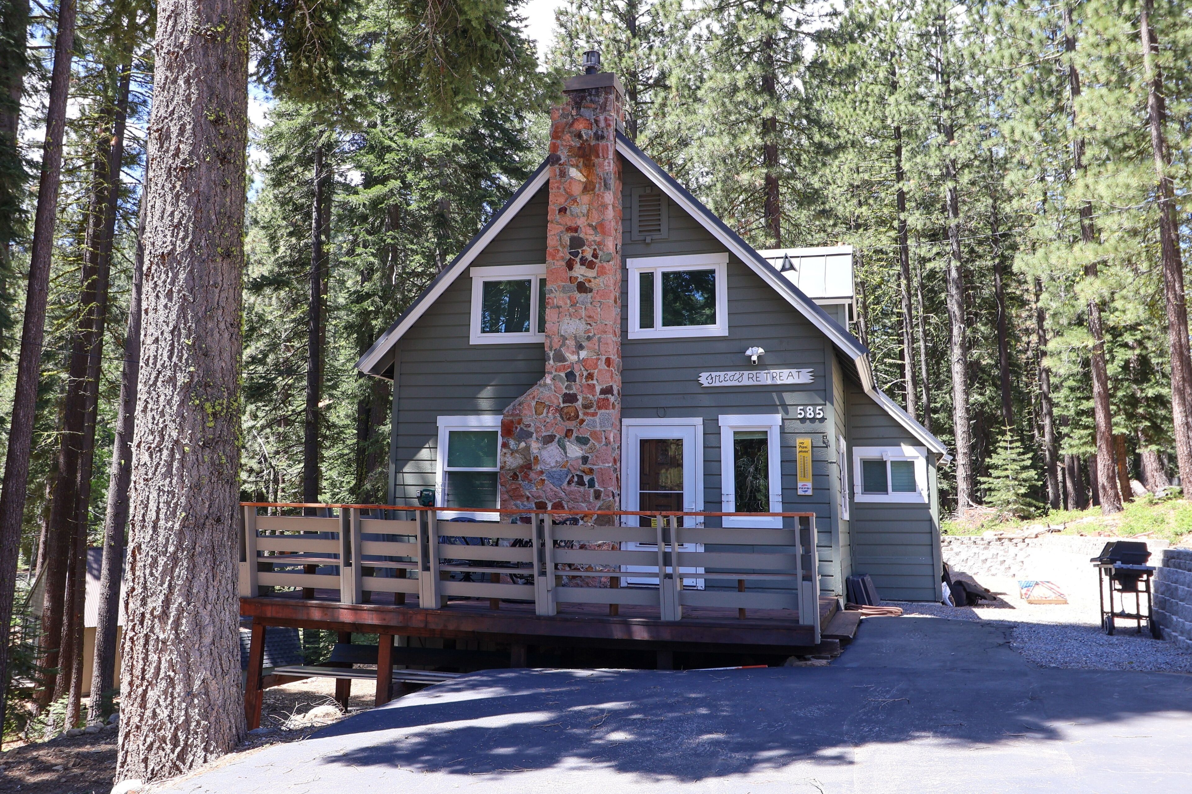 Un chalet doté d’une cheminée en pierre, d’une terrasse en bois et d’une enseigne indiquant qu’il s’agit d’un lieu de retraite.